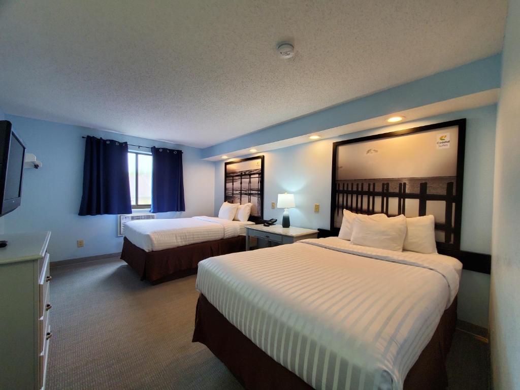 a hotel room with two beds and a television at Coastal Inn & Suites in Wilmington
