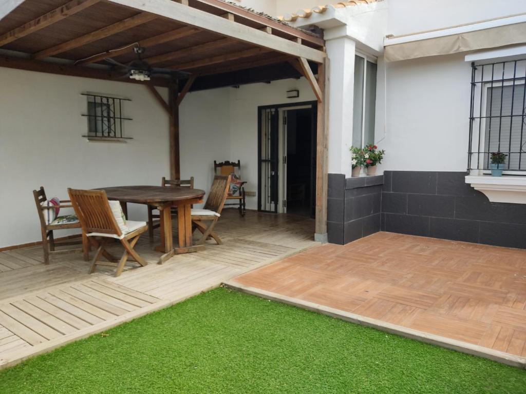 un patio con mesa, sillas y alfombra verde en Apartamento 700 metros de la playa en Playa Flamenca
