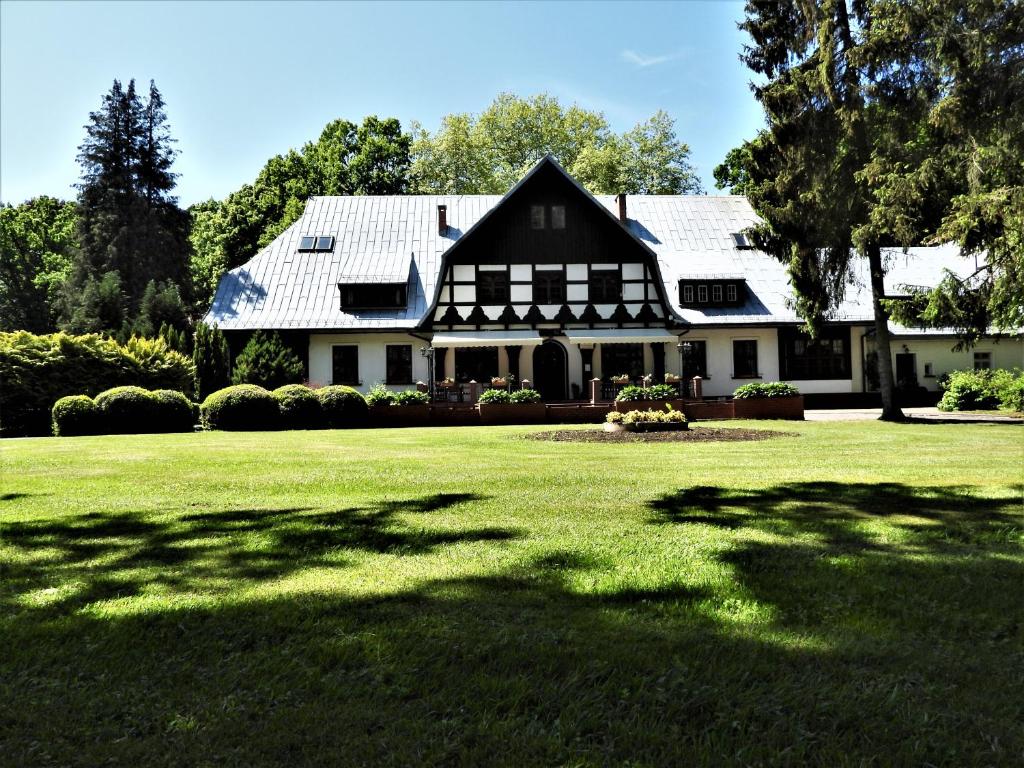 una casa bianca e nera con un ampio cortile di Dworek Osiecki a Osieki