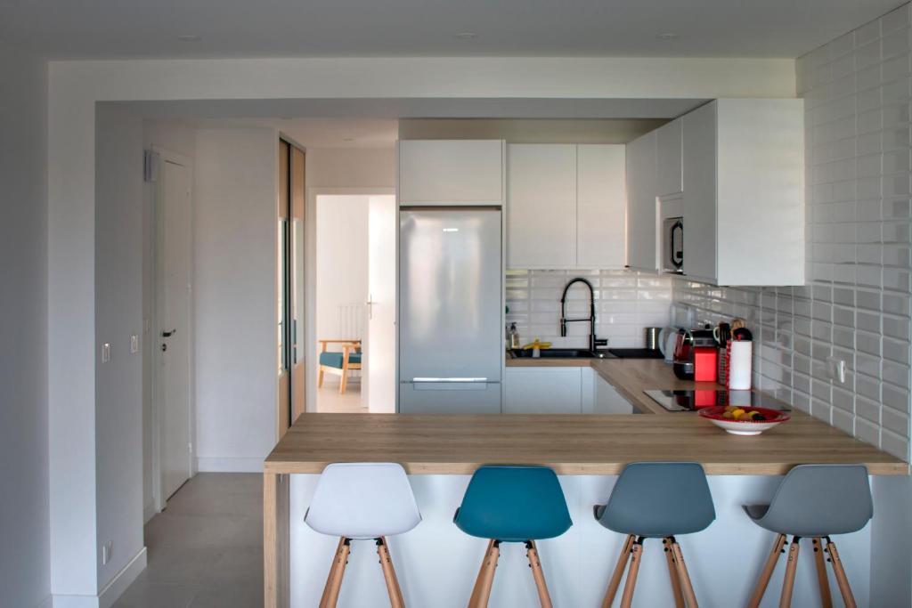 une cuisine avec un comptoir avec trois tabourets bleus dans l'établissement Appartement rénové, terrasse vue mer, à Cagnes-sur-Mer