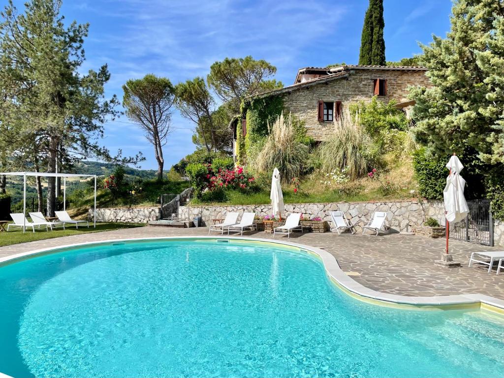 uma piscina em frente a uma casa em La Panoramica Gubbio - Maison de Charme - Casette e appartamenti self catering per vacanze meravigliose! em Gubbio