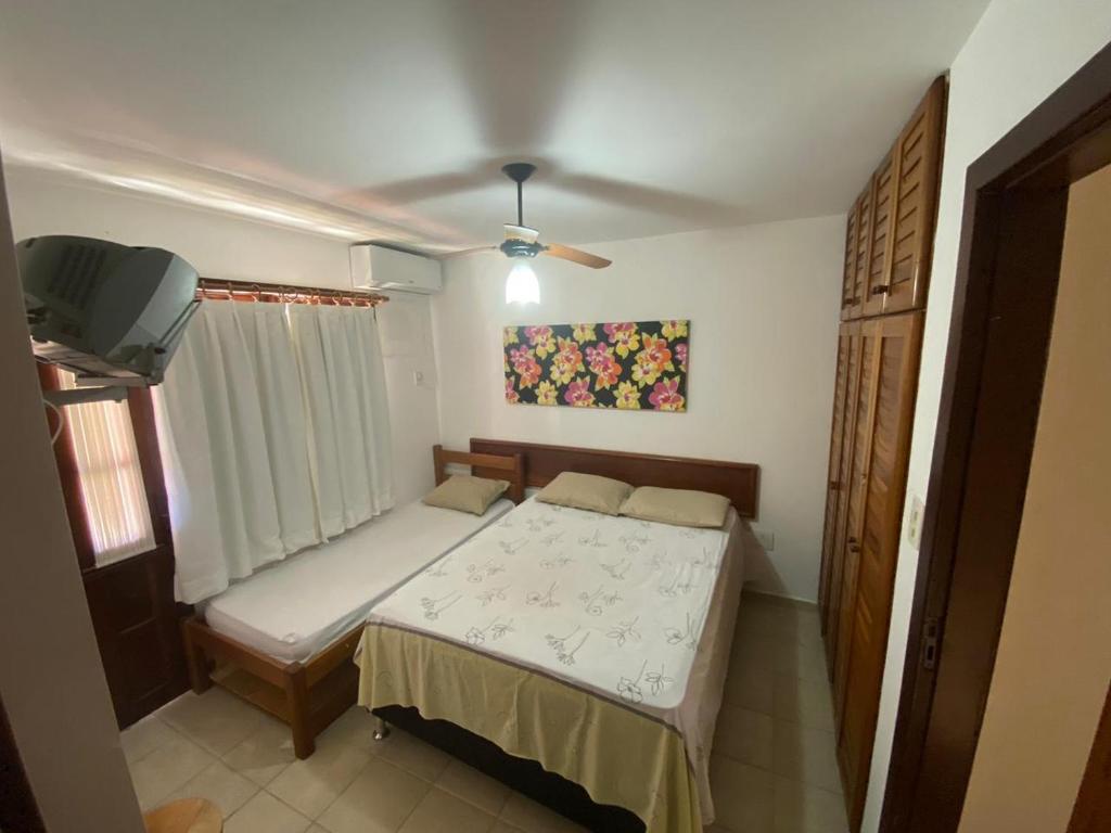 - une petite chambre avec un lit et une télévision dans l'établissement Apartamento Village do Bosque - a 200 metros da praia, à Porto Seguro