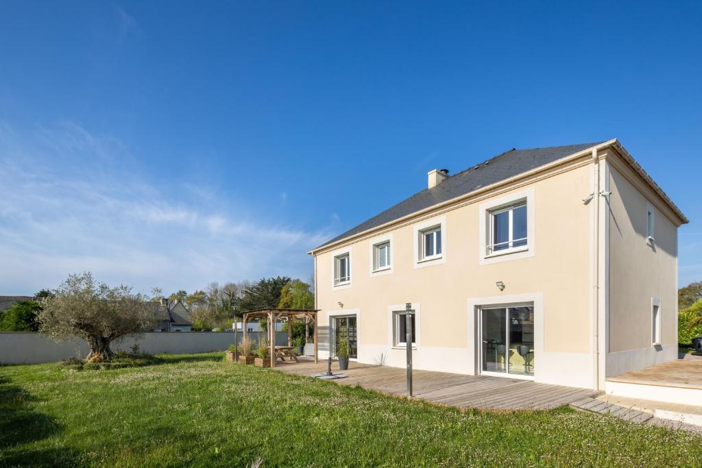 ein großes weißes Haus mit einer Holzterrasse in der Unterkunft La Baie Blanche - Maison contemporaine à Saint-Cast-Le-Guildo in Saint-Cast-le-Guildo