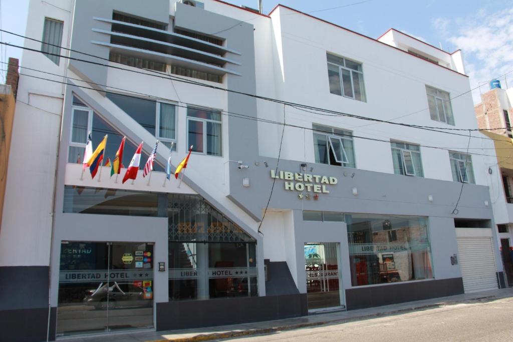 un hotel con banderas frente a un edificio en Libertad Hotel, en Trujillo