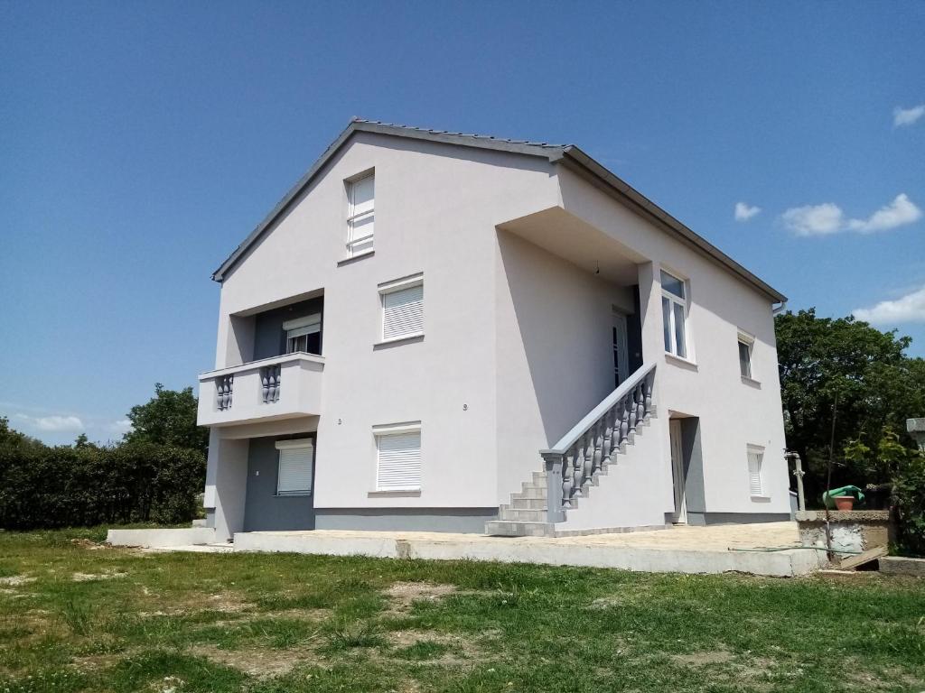 une maison blanche avec des escaliers sur son côté dans l'établissement Luka, à Galovac