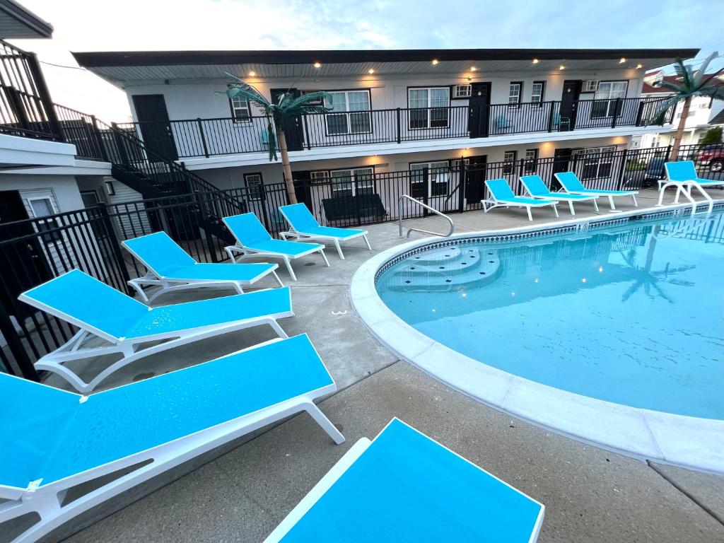a pool with blue lounge chairs next to a building at Brooklyn Beach Club in Wildwood