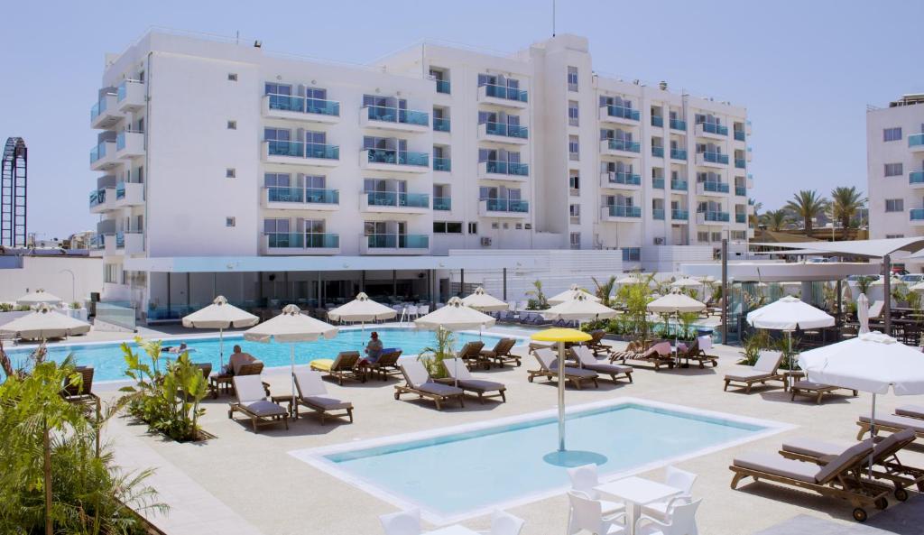 a hotel with a pool and chairs and a building at Kapetanios Bay Hotel Protaras in Protaras