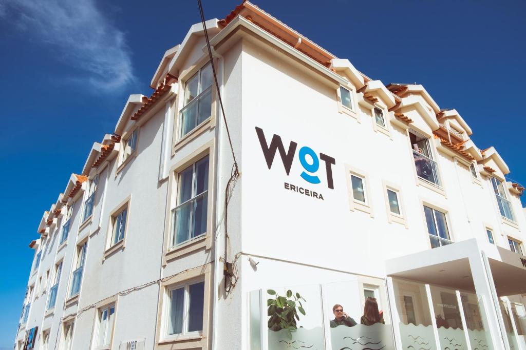 een wit gebouw met een wvu-bord erop bij WOT Ericeira in Ericeira