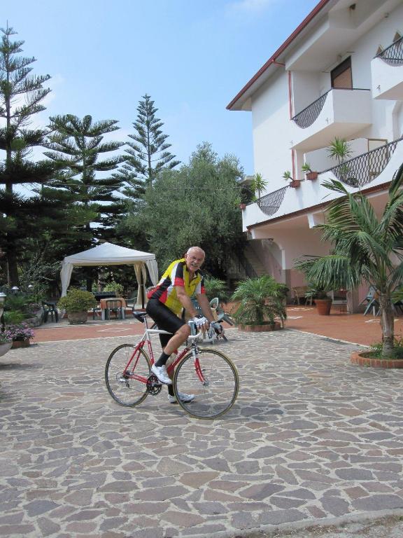 a man riding a bike in a courtyard at Hotel Royal in Coccorino