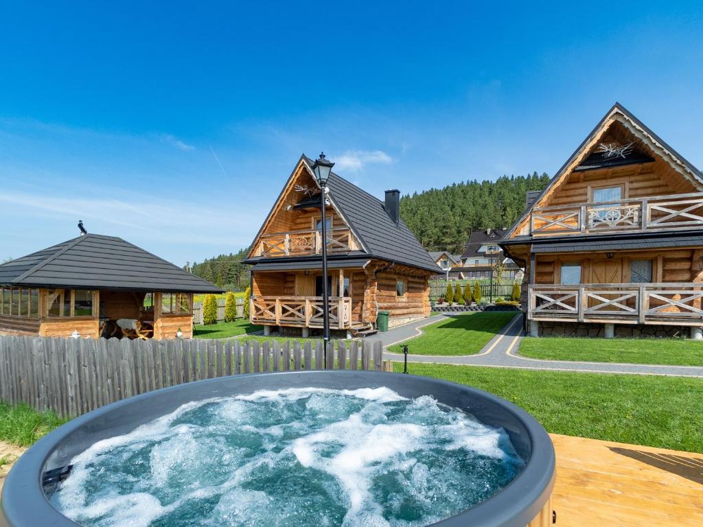 a hot tub in front of two log homes at Osada Szaflary in Szaflary
