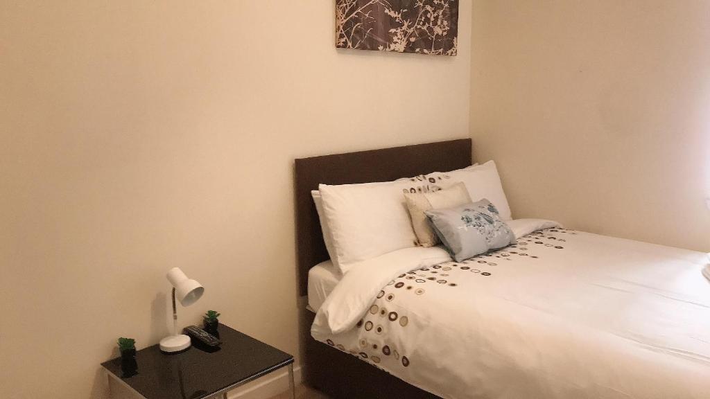 a bedroom with a bed with white sheets and pillows at Charming 2-Bedrooms City Centre Apartment-No Party in Aberdeen