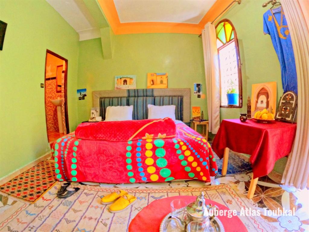 a bedroom with a bed covered in colorful sheets at Auberge Atlas Toubkal in Imlil