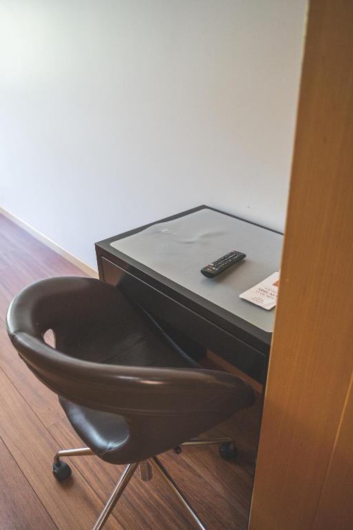 a chair sitting next to a desk with a remote control at Hotel De Cerva in Cerva