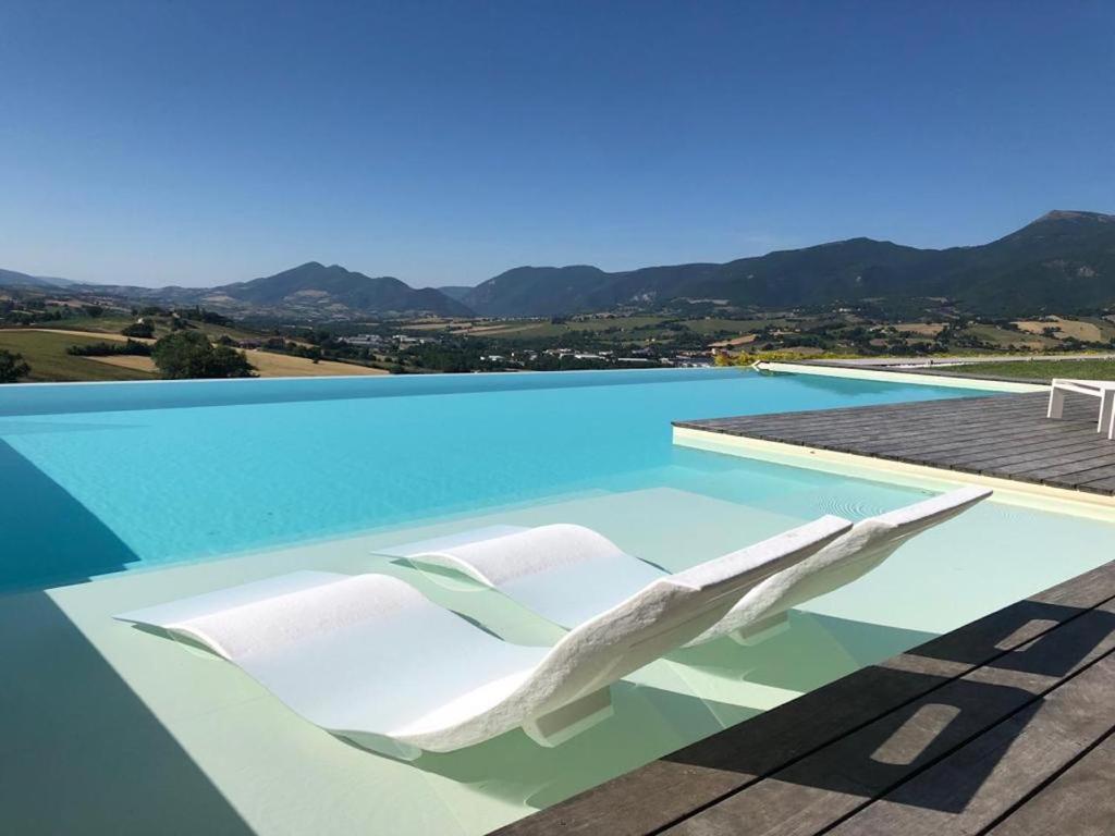 einen weißen Sessel auf einem Pool in der Unterkunft Serre Alte Landscape Luxury Rooms in Matelica
