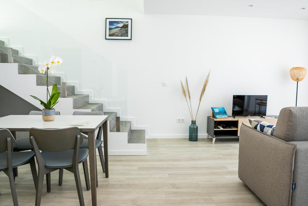 a living room with a table and chairs and stairs at TRIADE Apartamentos in Aveiro