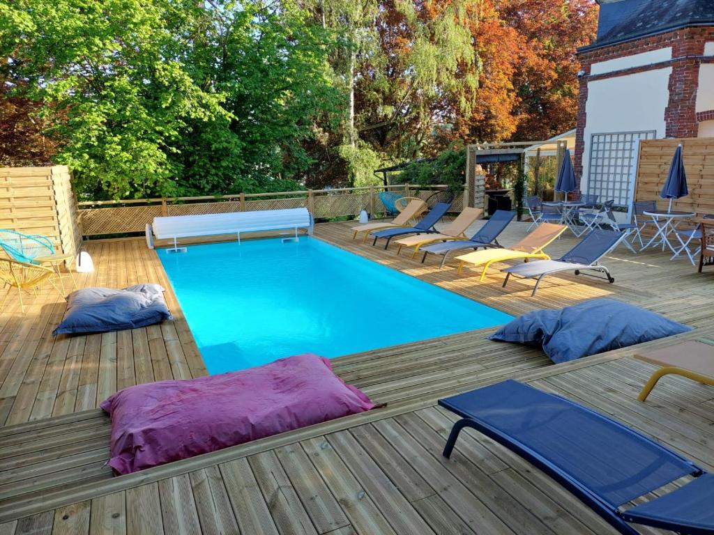 een zwembad met ligstoelen en een terras bij Le Clos des Lodges in Bernay