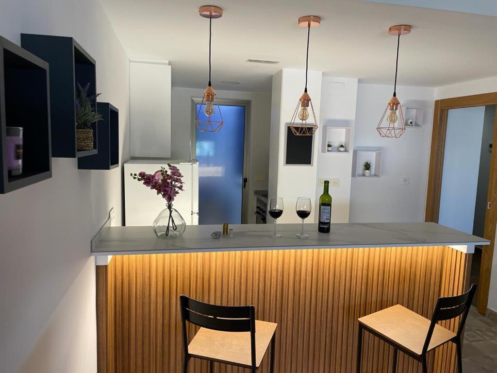 a kitchen with a bar with two chairs and wine glasses at Apartamento El Azul in Molina de Segura