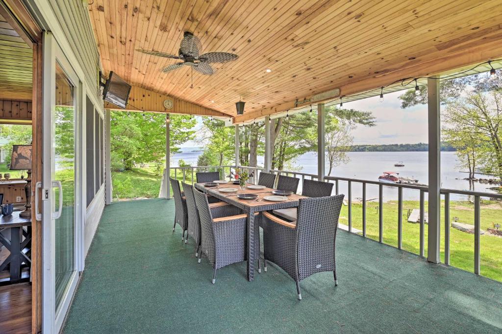 Lakefront Gloversville Home with Beach and Dock! في Broadalbin: شاشة في الشرفة مع وجود طاولة وكراسي