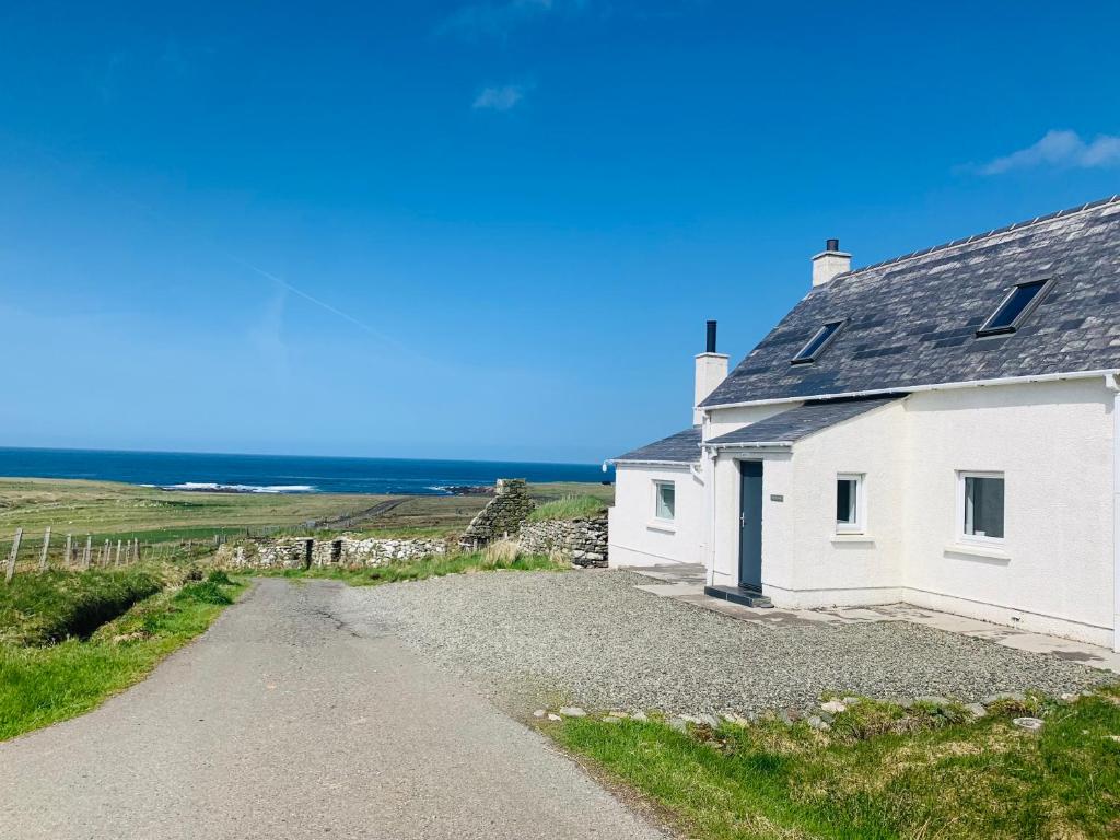 a white cottage on a gravel road at Old Croft House Cottage, Isle of Lewis in Borve