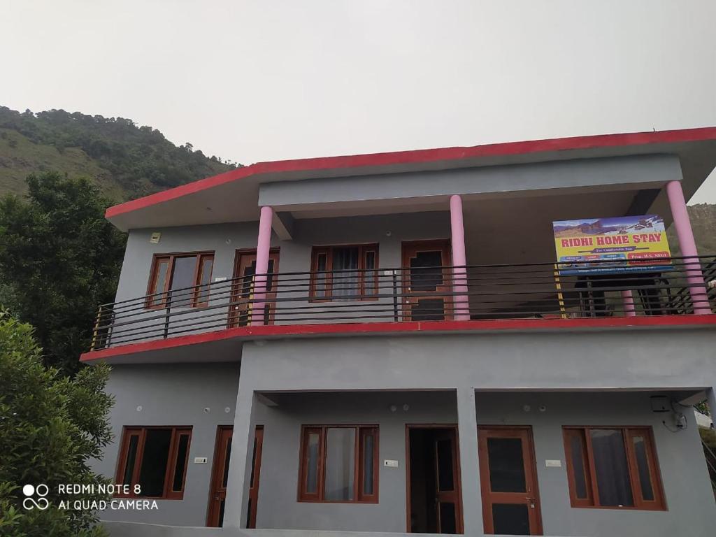 un edificio con balcón y una señal en él en Ridhi Homestay Sari, en Ukhimath