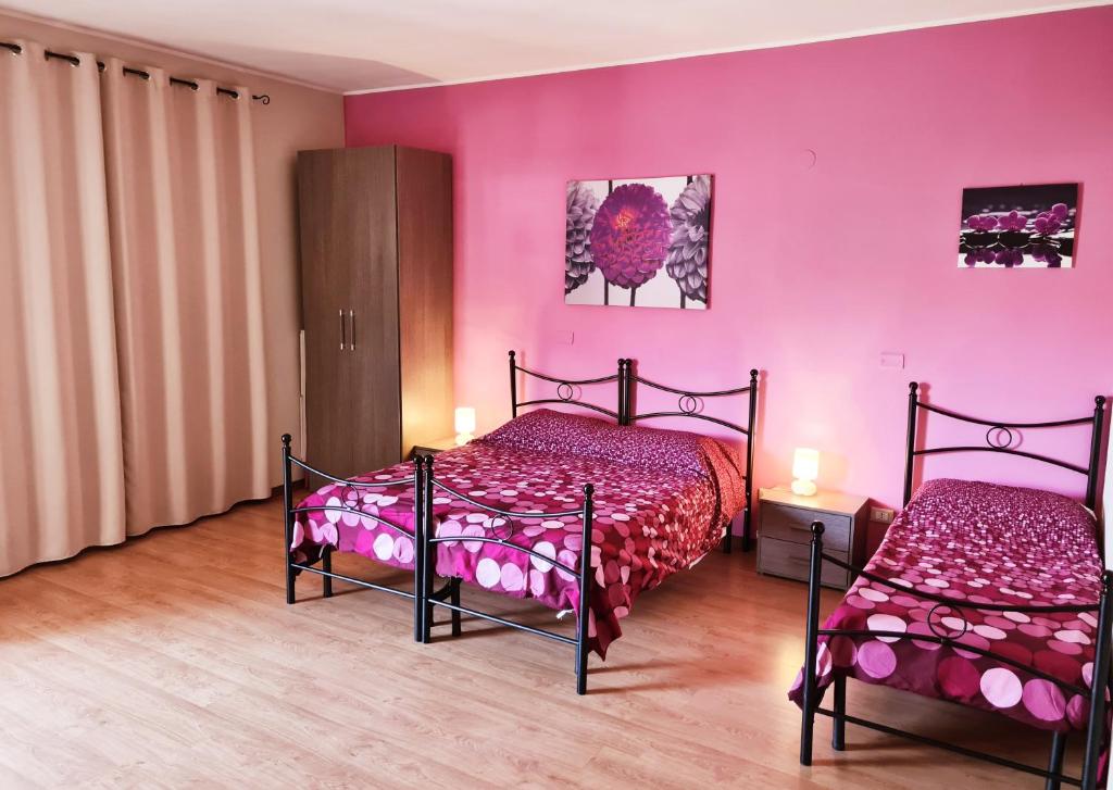 2 camas en una habitación con paredes rosas en Affittacamere Il Terrazzo Di Archimede, en Siracusa