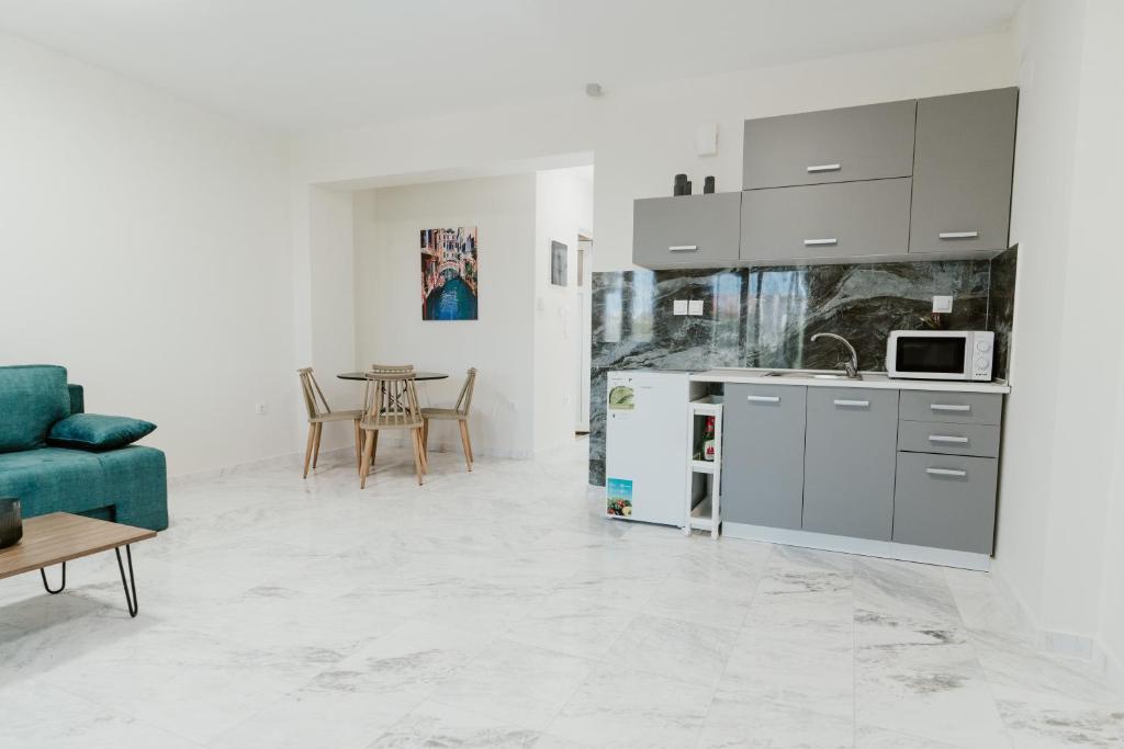 eine Küche und ein Wohnzimmer mit einem blauen Sofa in der Unterkunft BLUE AND WHITE LUXURY suites in Nea Kallikratia