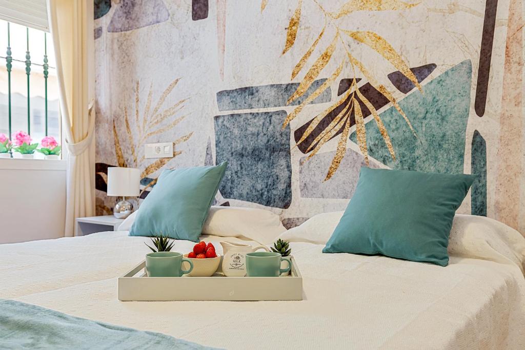 uma cama com duas almofadas azuis e uma bandeja com plantas em Coral Apartment La Cala Beach em La Cala de Mijas