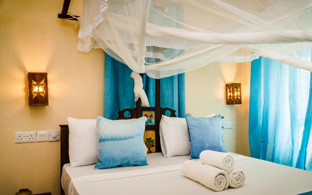 Emerald Palm في مدينة زنجبار: غرفة نوم بسريرين مع ستائر زرقاء