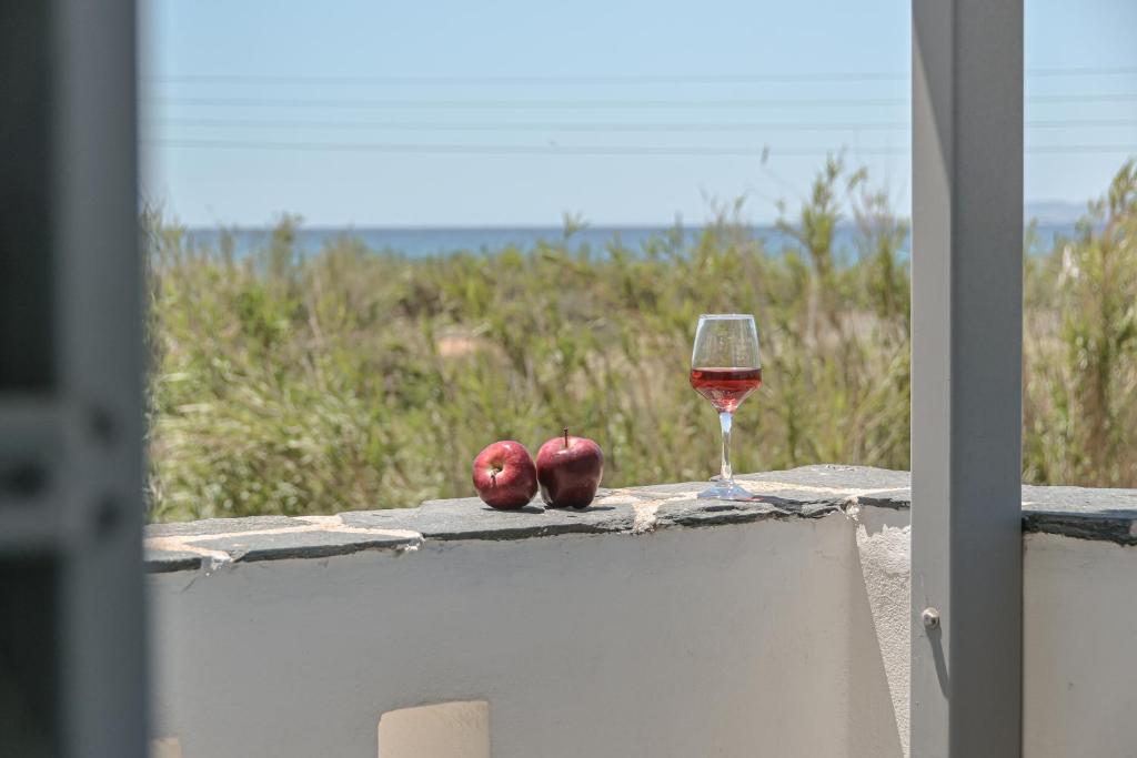 um copo de vinho e duas maçãs numa saliência em Vive Mare Plaka II em Naxos Chora
