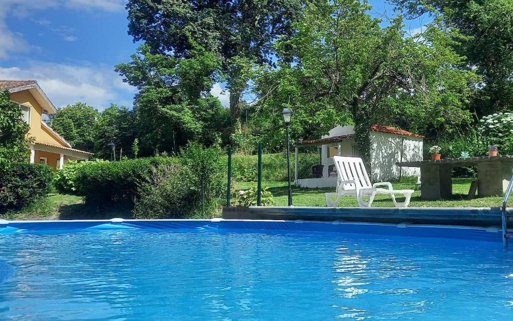 une piscine bleue avec une chaise blanche et une table dans l'établissement Casa Solda, una casa con piscina en Gondomar, à Gondomar