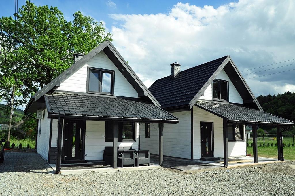 uma casa branca com um telhado preto em Domki u Biesiady em Lesko