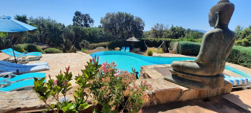 une villa avec une piscine et une statue dans un jardin dans l'établissement Villa des Delices, à Grimaud