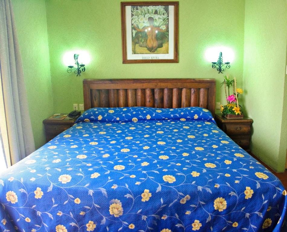 a bed with a blue comforter with flowers on it at Hotel Plaza Independencia in Villahermosa