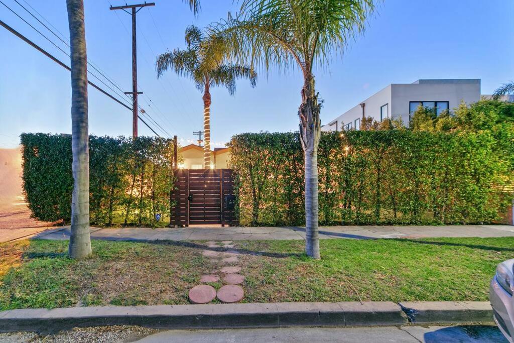 a yard with trees and a fence with palm trees at Beverly Grove Spanish Oasis with Pool & Parking in Los Angeles