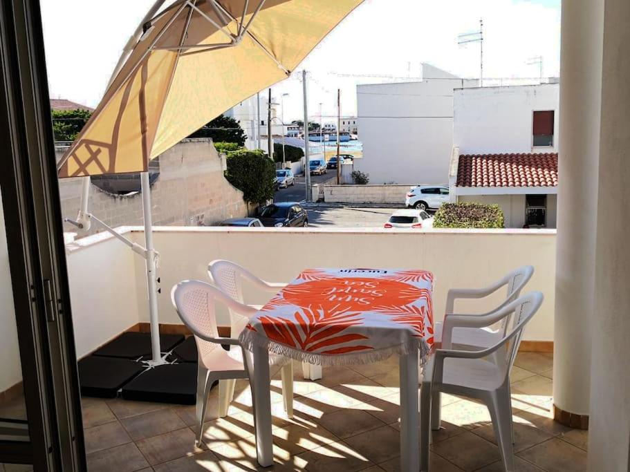 a table and chairs on a balcony with an umbrella at At home on the coast in Torre Santa Sabina