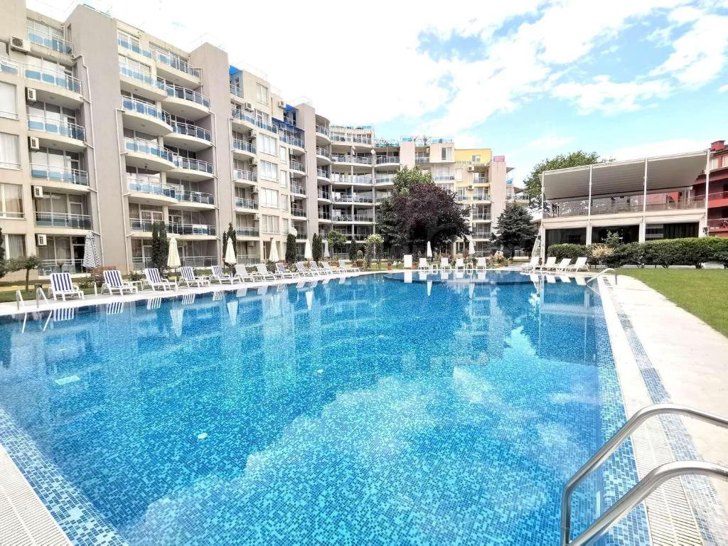 a large swimming pool with white chairs and buildings at Dadi Oazis Ravda in Ravda