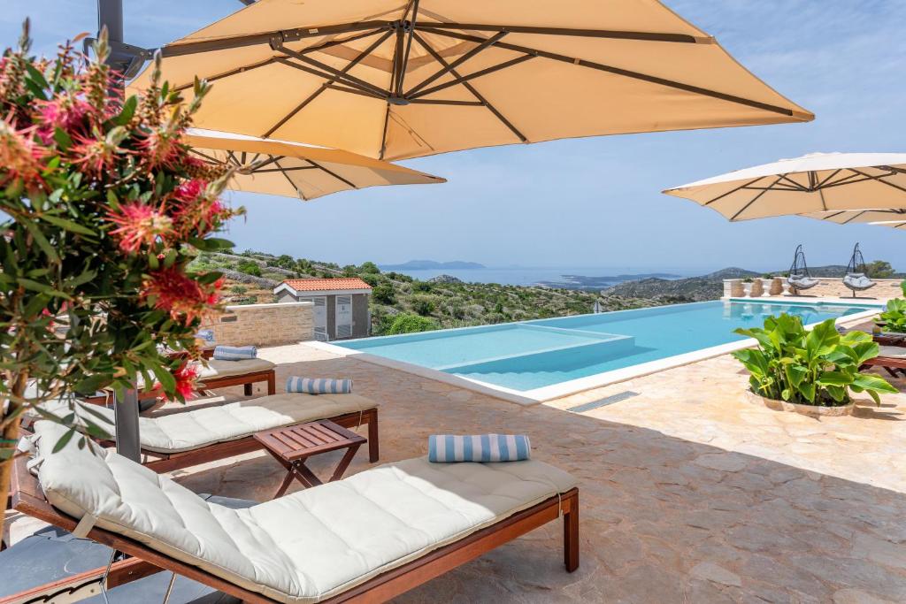 un patio con sombrillas y una piscina en Vidikovac Levanda Luxury Apartments en Hvar