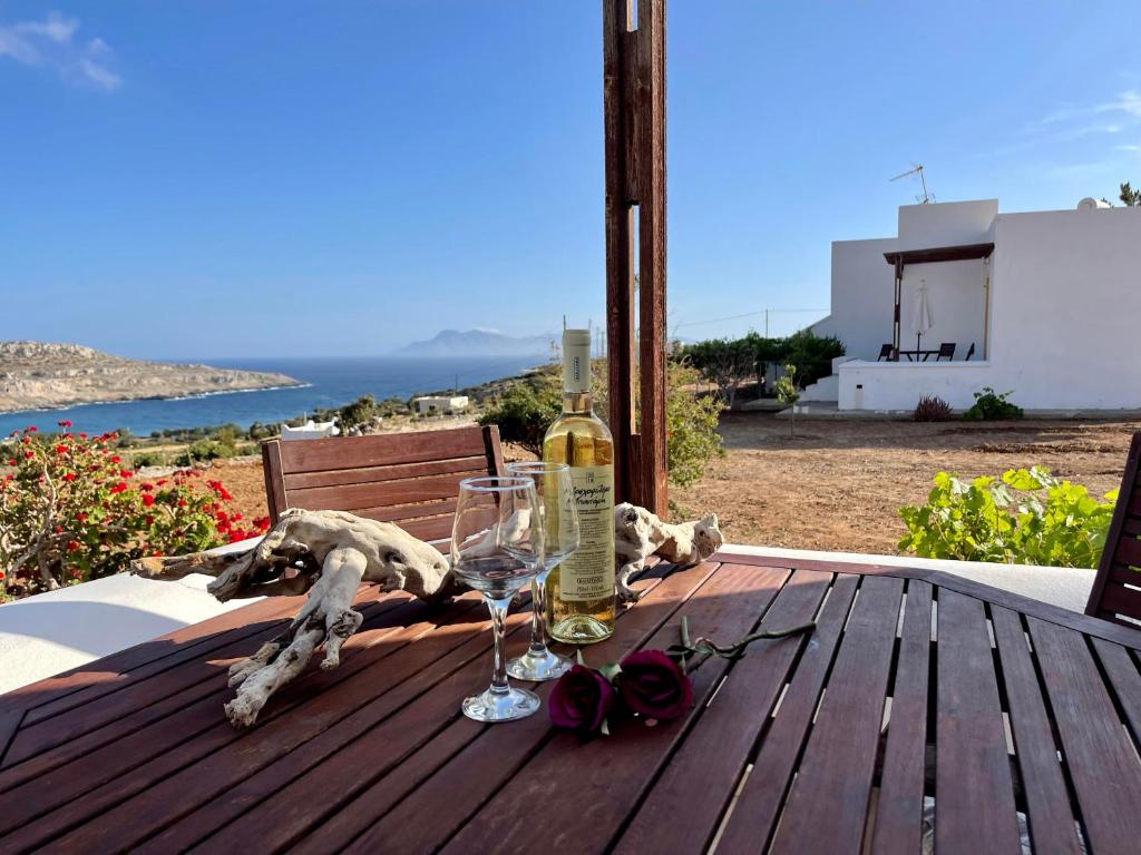 a wooden table with a bottle of wine and glasses at Dream Villas in Lefkos Karpathou