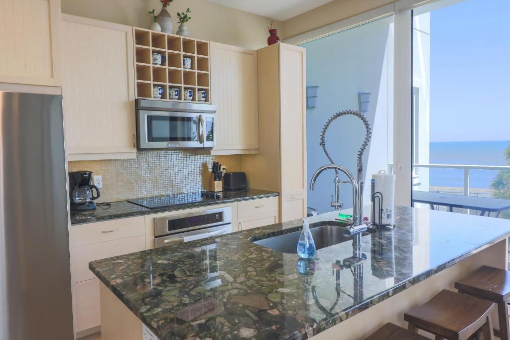 a kitchen with a counter with a sink and a window at Beachfront Laid Back and Luxurious Diamond Beach Condo - Amazing Pools Amenities in Galveston