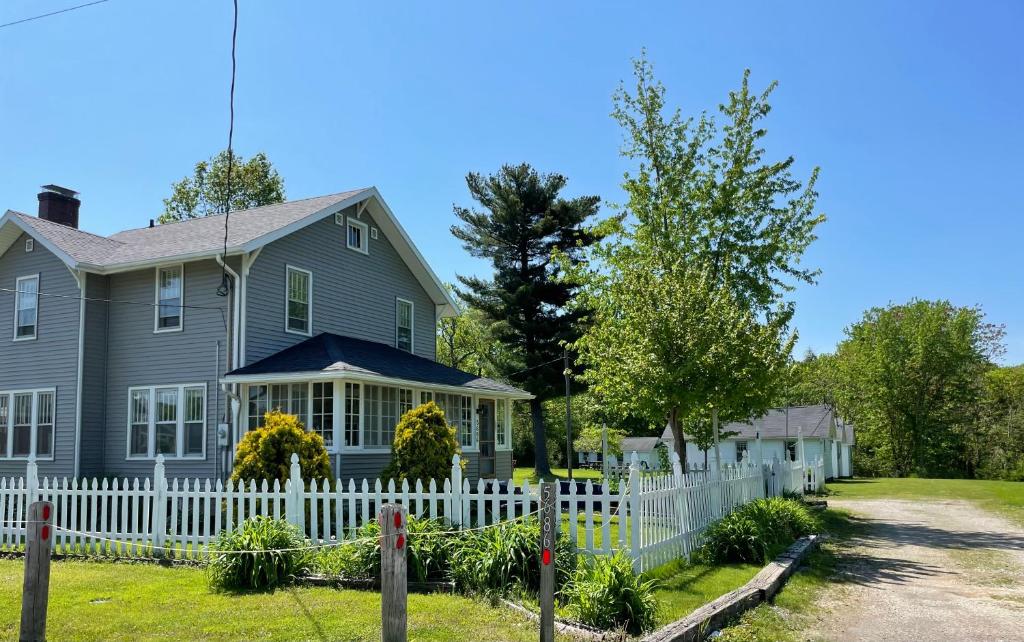 una casa con una cerca blanca delante de ella en Drop Anchor Cottages and Lake House en Geneva-on-the-Lake