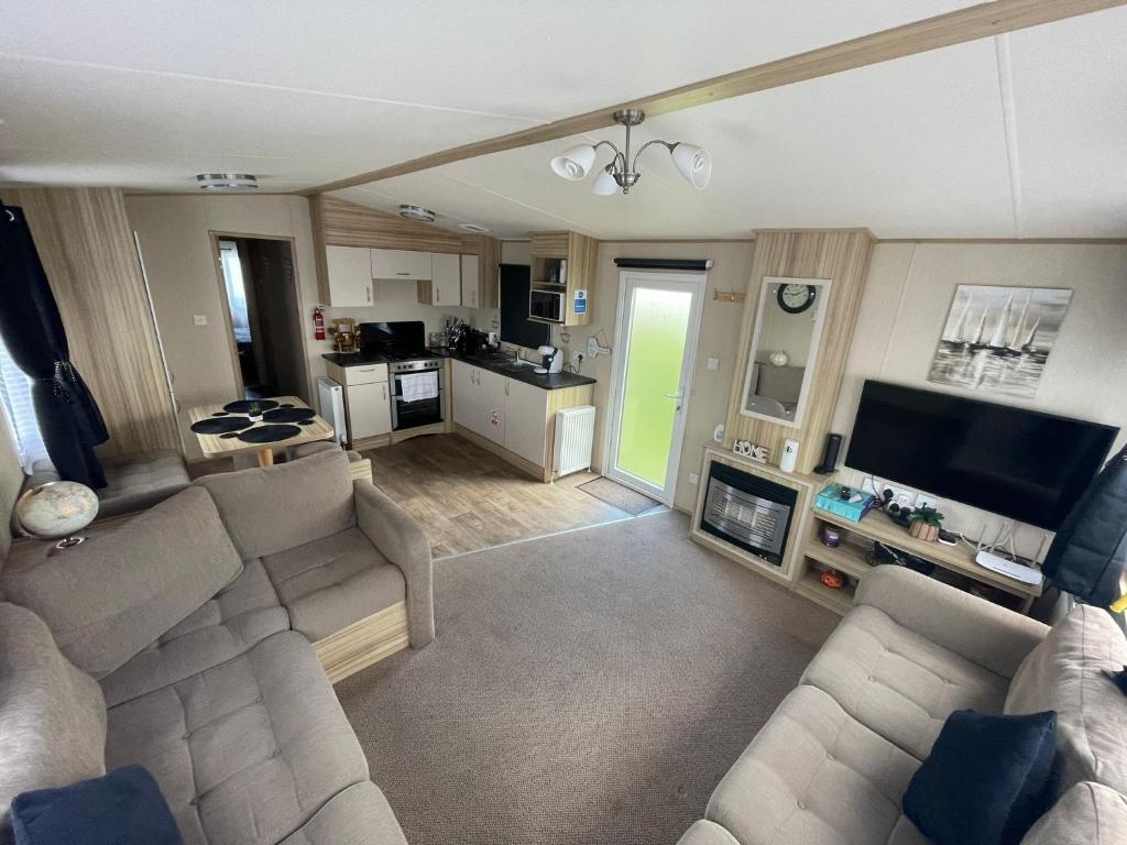 een woonkamer met een bank en een tv en een keuken bij Holiday Park Caravan Fluffy in Harts Holiday Park in Leysdown-on-Sea