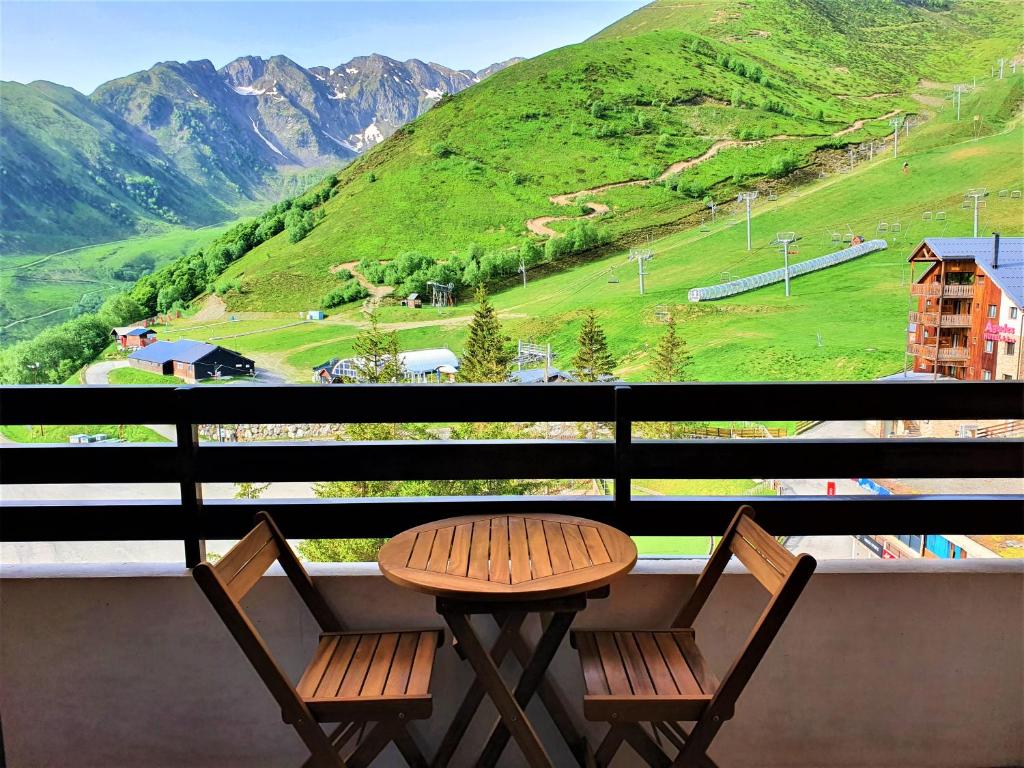 een tafel en 2 stoelen op een balkon met een berg bij Appartement à la montagne avec vue Imprenable in Gouaux-de-Larboust