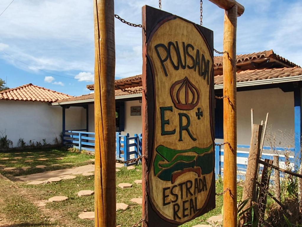 a sign on a pole in front of a house at Pousada Estrada Real in Milho Verde