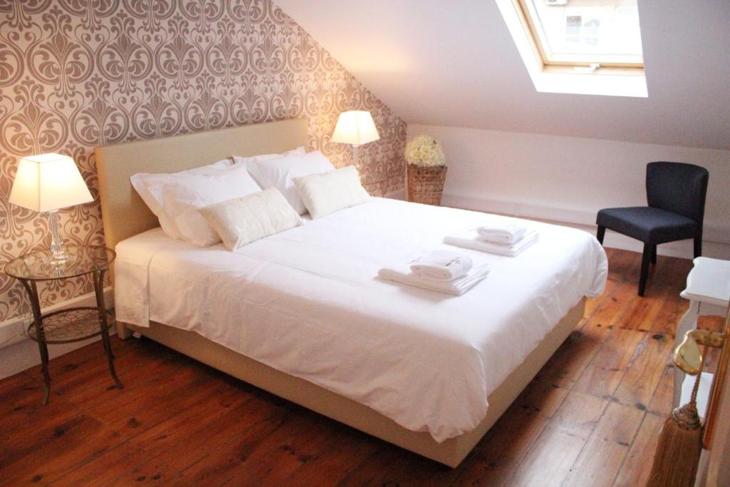 um quarto com uma grande cama branca e uma cadeira em The Sky Lofts Lisbon - Guesthouse em Lisboa
