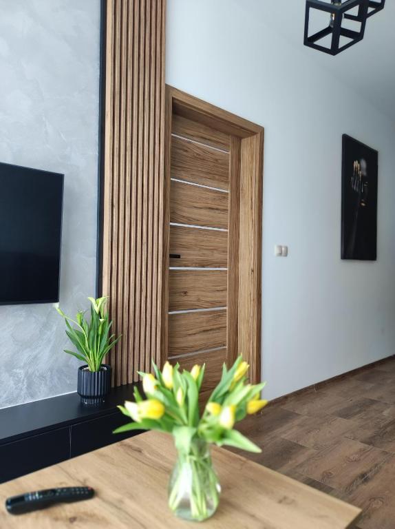 a room with a wooden door and a table with flowers at Silver 58 Zator in Zator