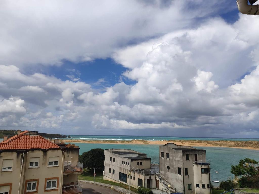 uitzicht op een waterlichaam en sommige gebouwen bij Apartamento con vistas al mar-Ola del atardecer in Mogro