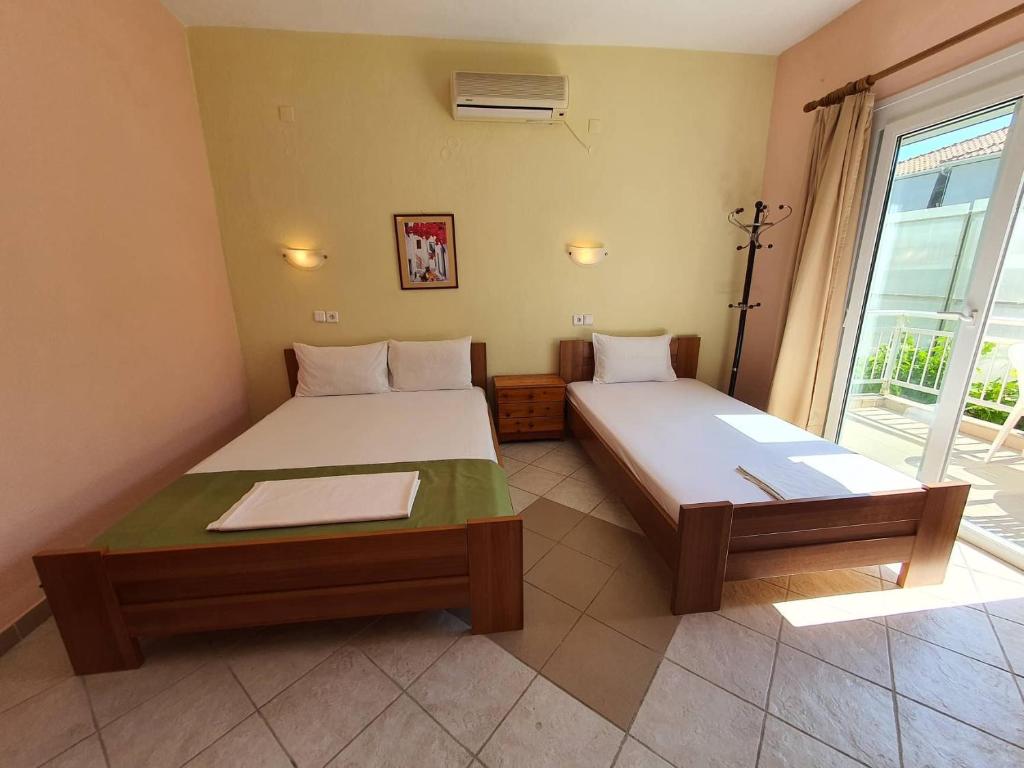 a room with two beds and a large window at Studios Kyriaki in Limenaria