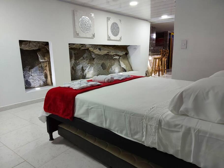 een slaapkamer met een bed met een rode deken erop bij La Casa de La Piedra in Guatapé