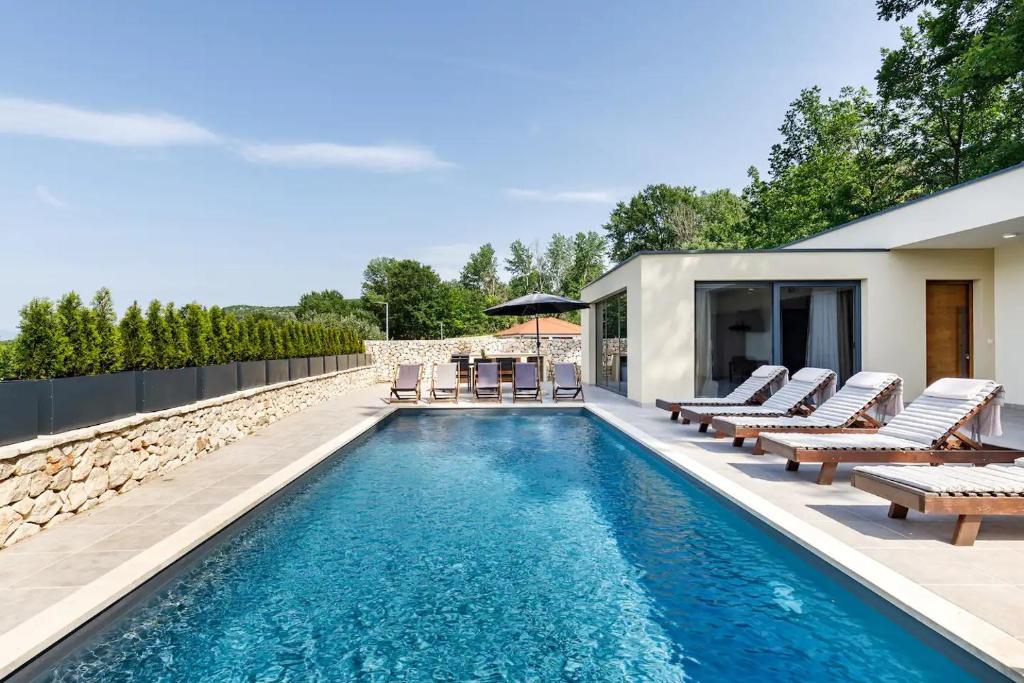 une piscine avec des chaises longues et une maison dans l'établissement Villa Noel, à Međugorje