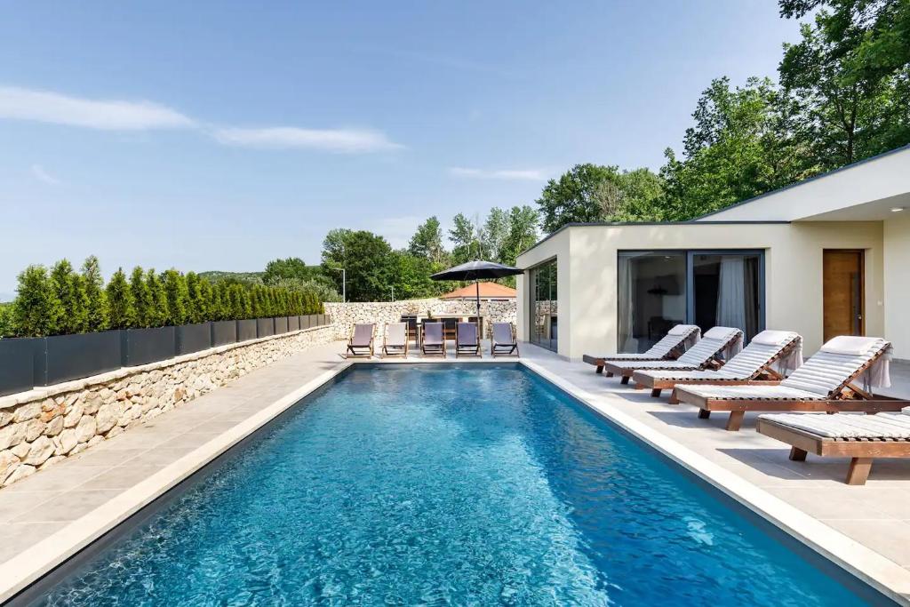a swimming pool with lounge chairs and a house at Villa Noel in Međugorje